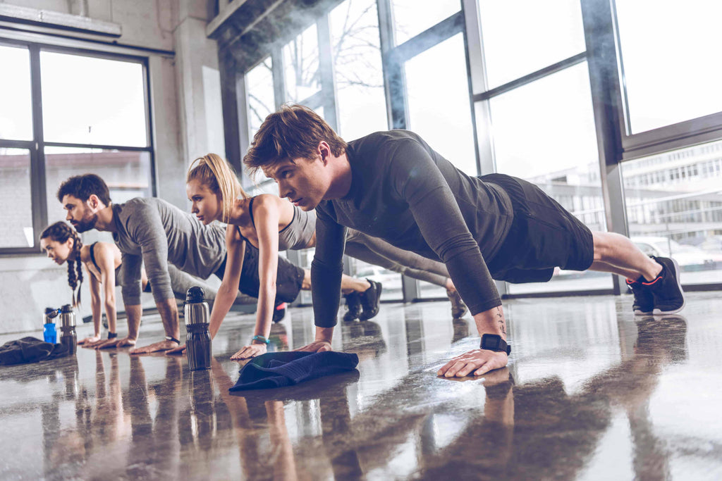 co-ed group exercise with 4 people in a push up position
