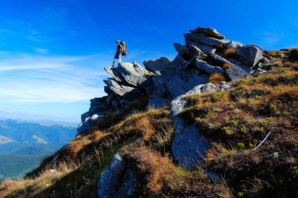 man-hiking-standing-on-rocks