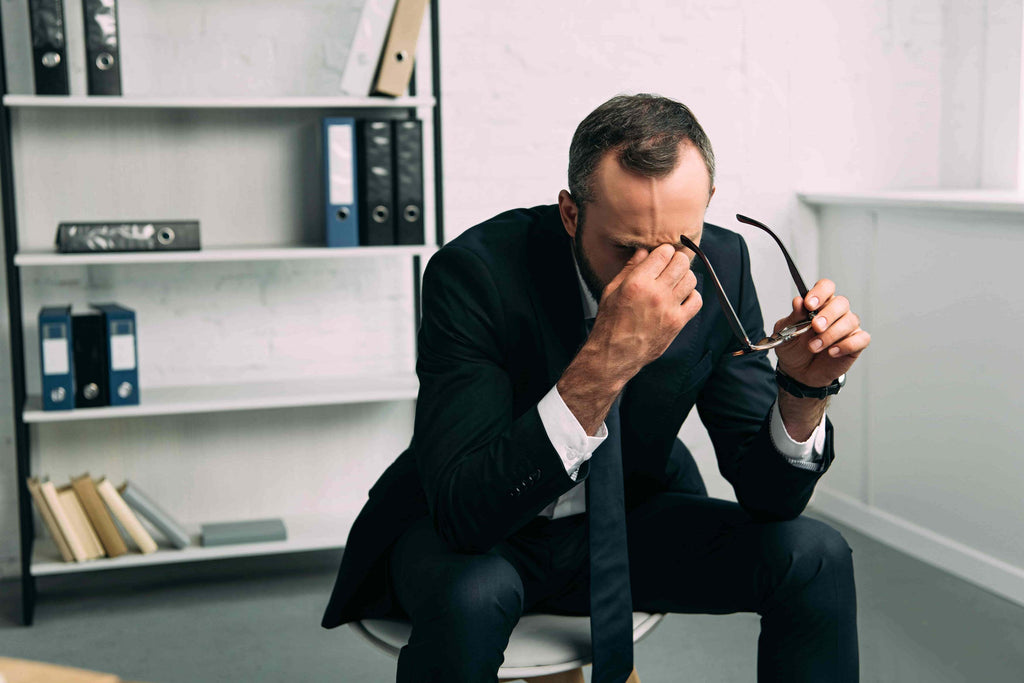 overworked businessman in suit with eyeglasses in office
