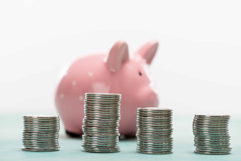 stacks of quarters with a piggy bank in the background