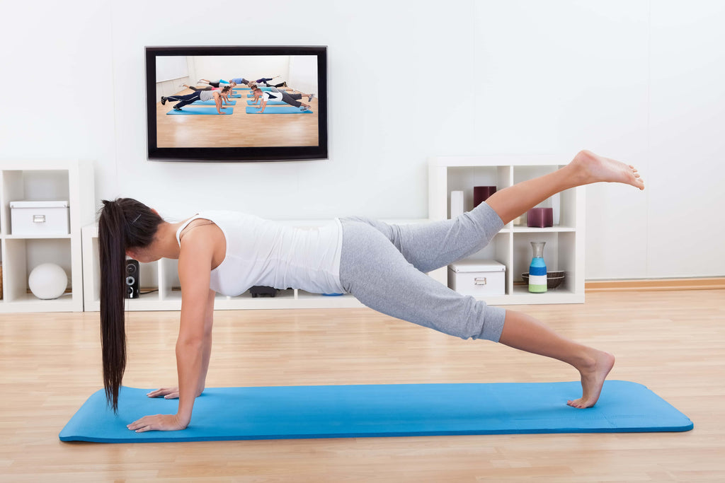 woman working out from home as she watches a workout video in her living room